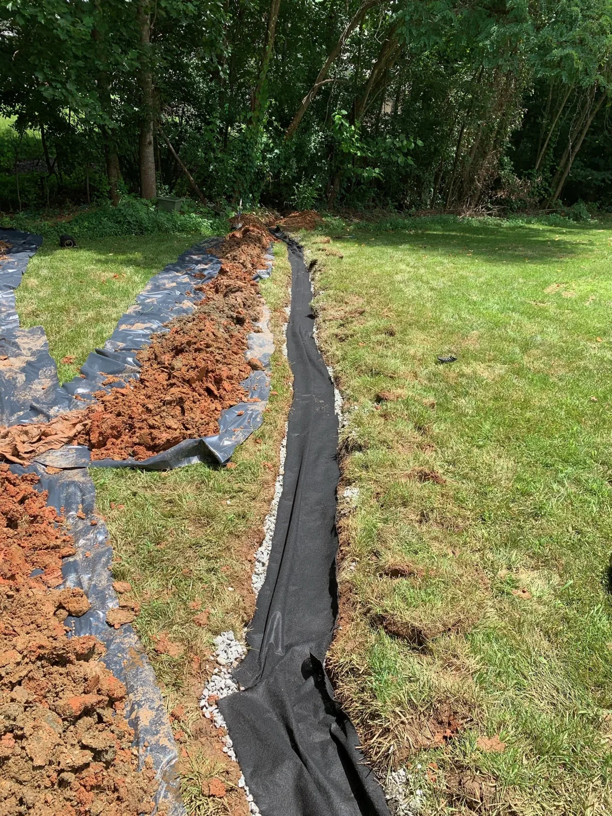 Exterior drainage trench being installed through a lawn