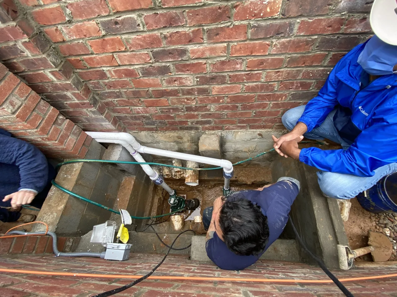 Drainage installation work beside a brick foundation